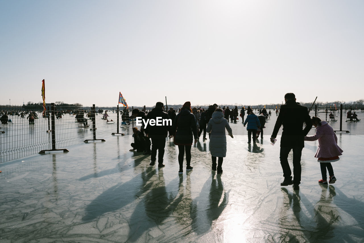 Rear view of people walking on frozen lake