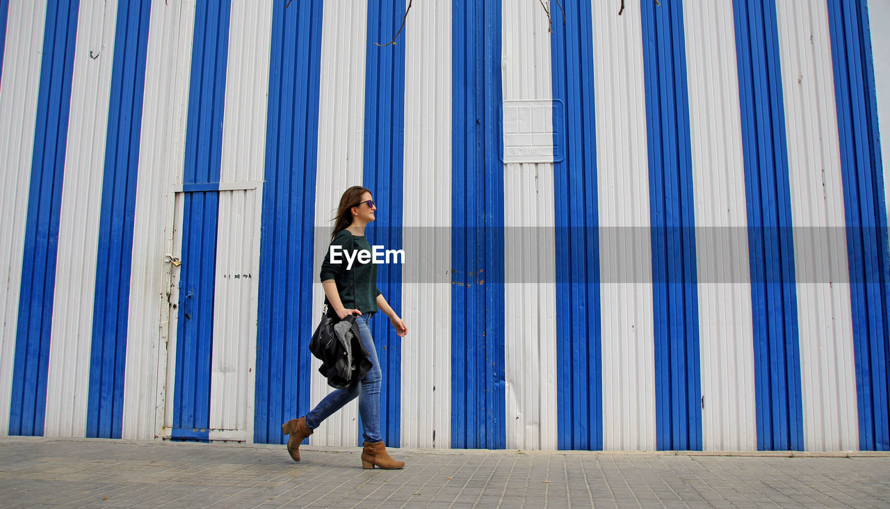 Woman walking by striped built structure