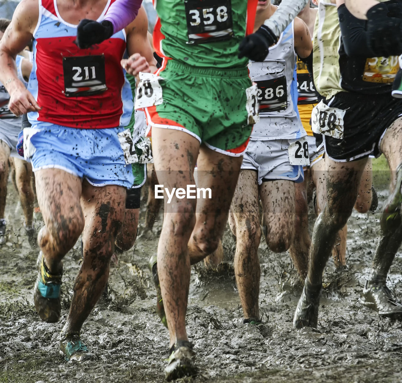 Runners racing a high school championship 5k in heavy mud with their spikes taped on with duct tape.