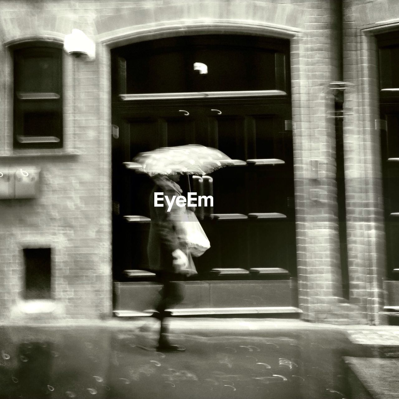 Side view of a blurred person with umbrella on rainy day