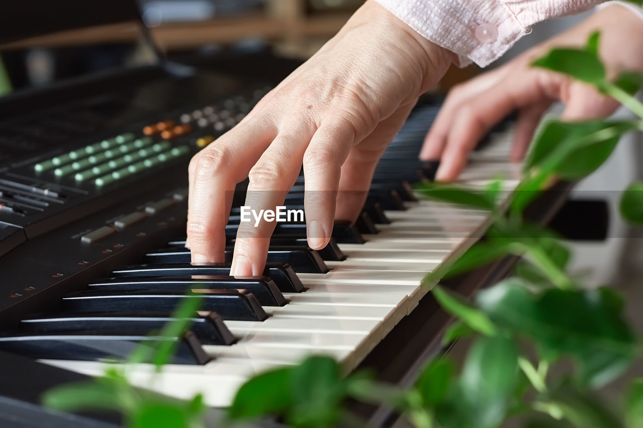 Female musician playing the digital piano or electronic keyboard at home. music education online
