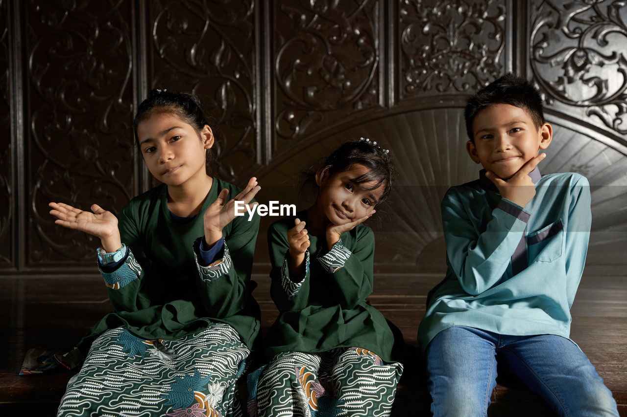 Malay kids with traditional clothing sitting together with hand gesture love