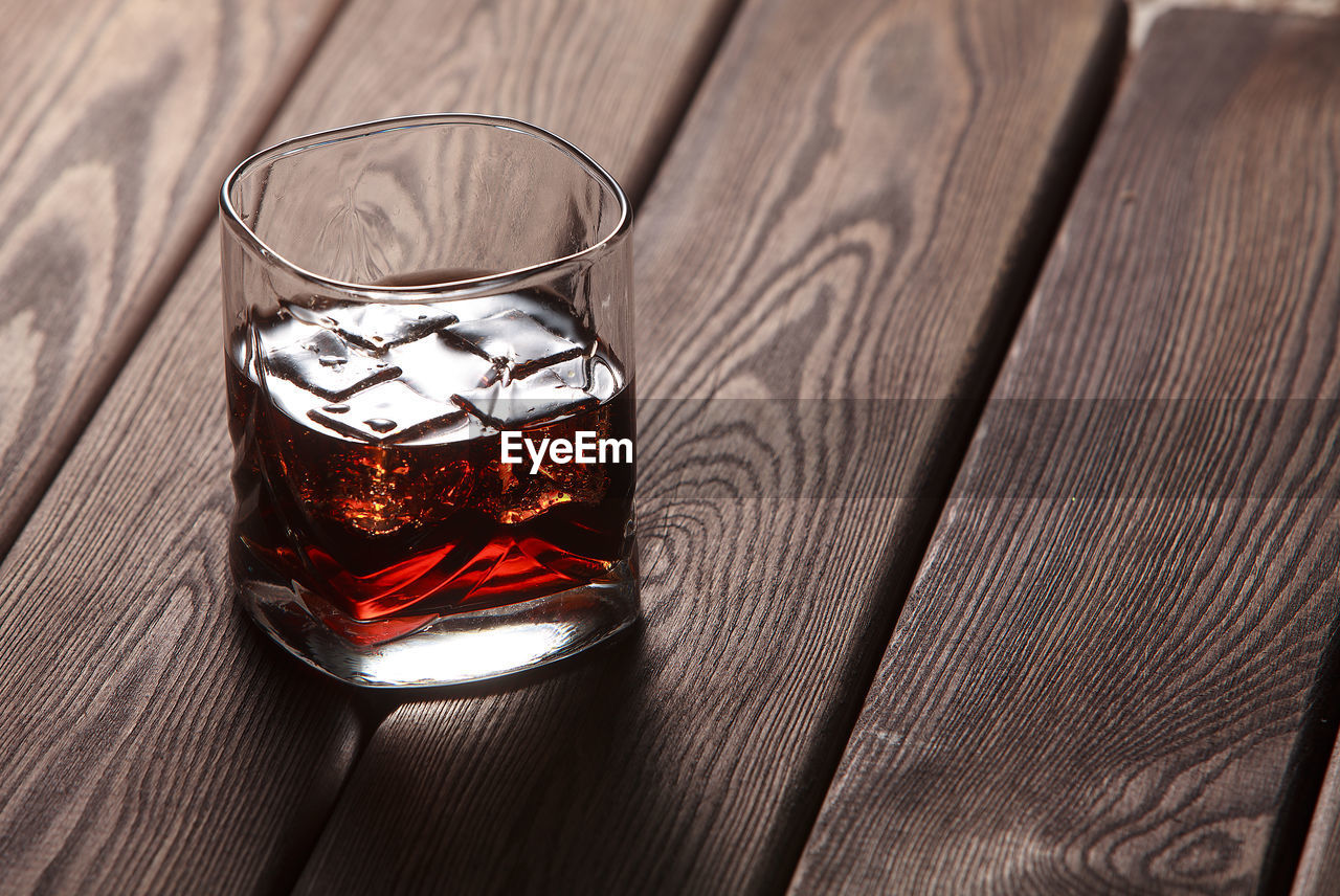 Whiskey in a glass with ice in a dark wooden background