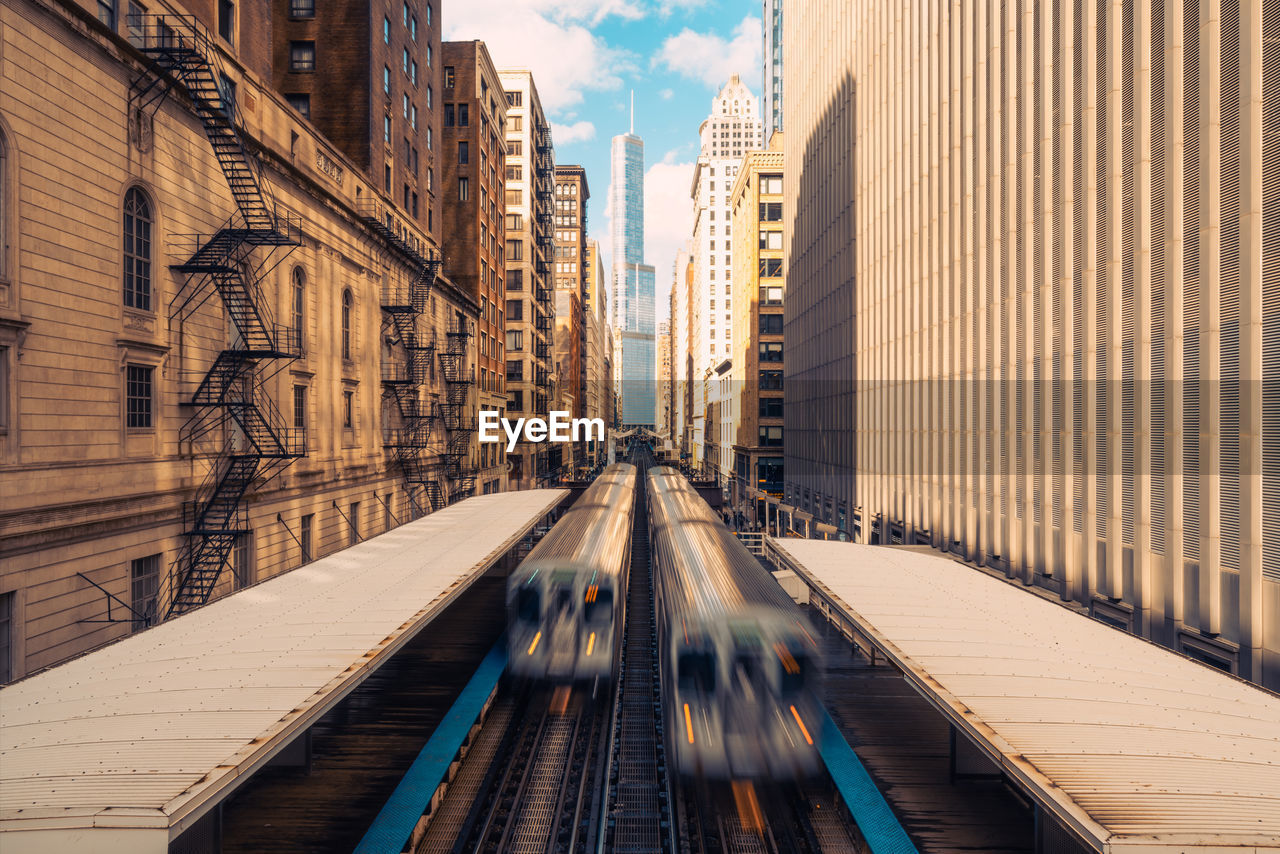 Blurred motion of trains amidst buildings in city