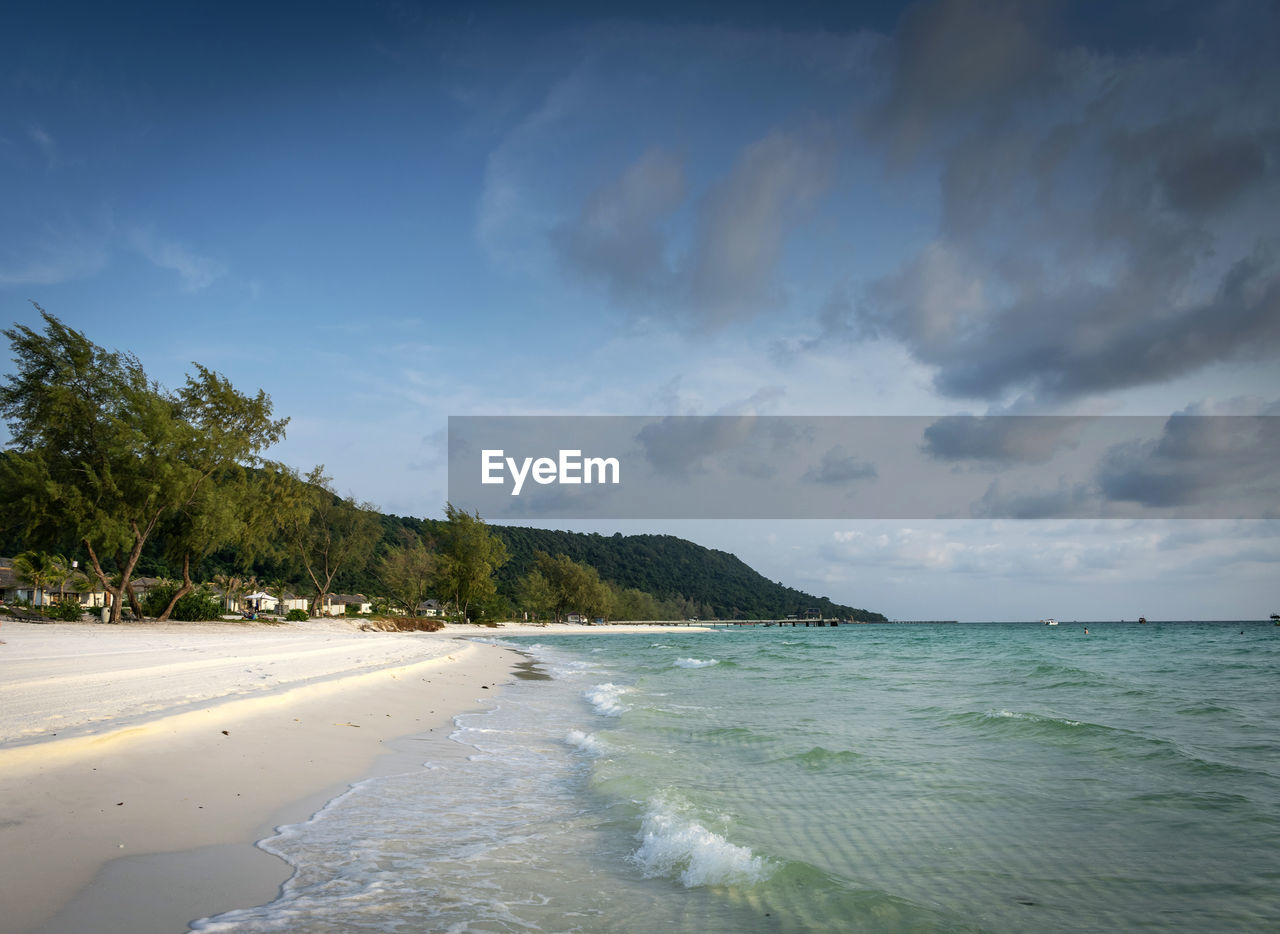 water, sea, land, beach, sky, scenics - nature, beauty in nature, sand, body of water, cloud, tropical climate, ocean, nature, shore, tree, wave, travel destinations, environment, palm tree, tranquility, travel, wind wave, coastline, island, plant, coast, tranquil scene, holiday, vacation, trip, landscape, sports, tourism, water sports, idyllic, surfing, motion, horizon, outdoors, seascape, coconut palm tree, water's edge, blue, tropical tree, tropics, day, summer, horizon over water, bay, non-urban scene, relaxation, lagoon