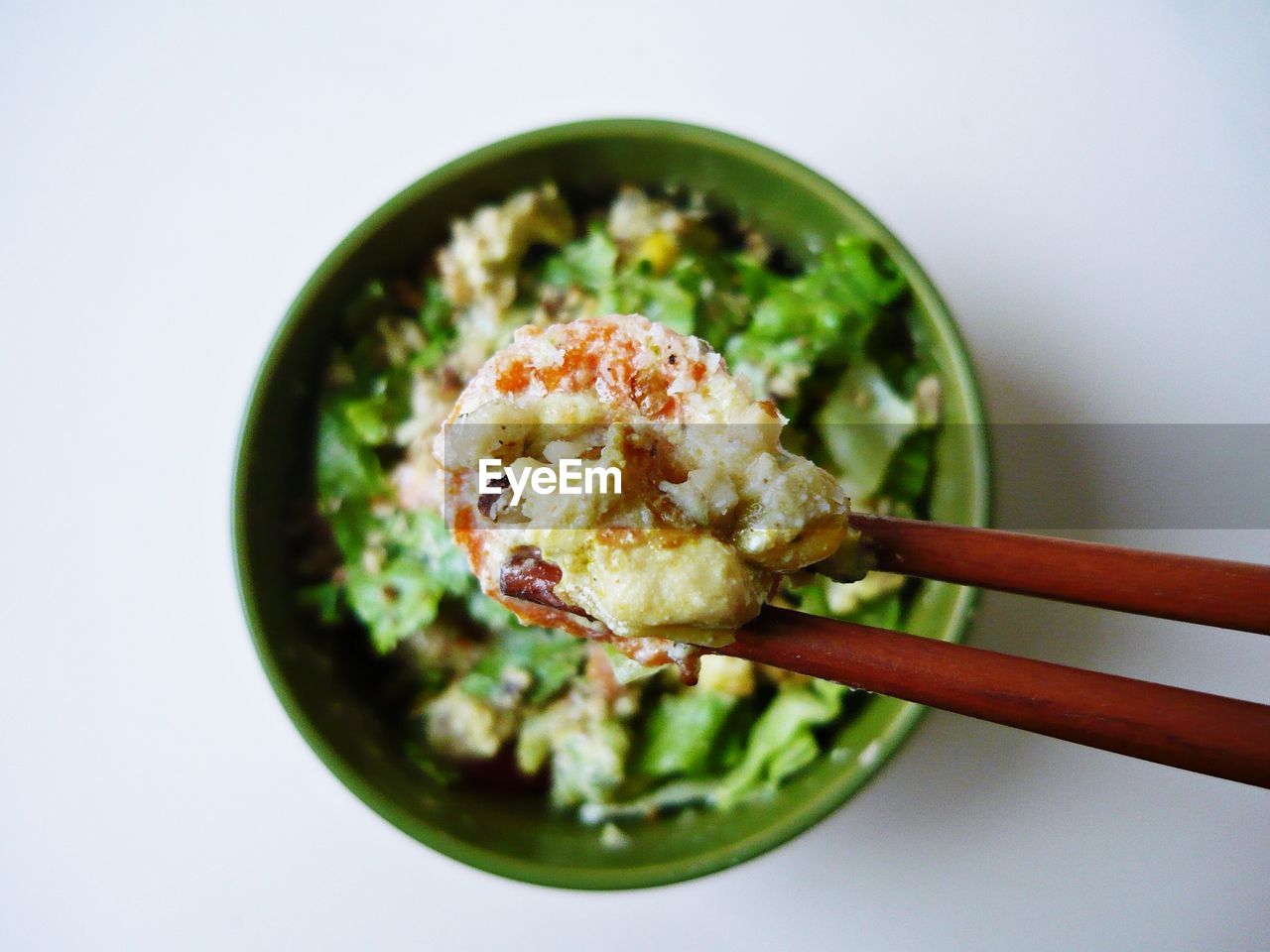 Close up of food in bowl with chopsticks over white background