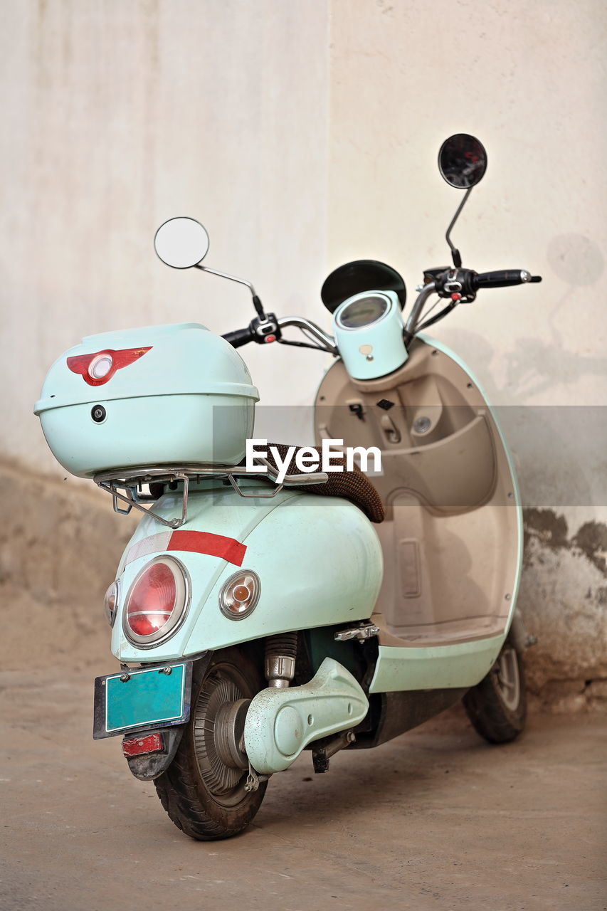 Close-up of scooter standing by wall