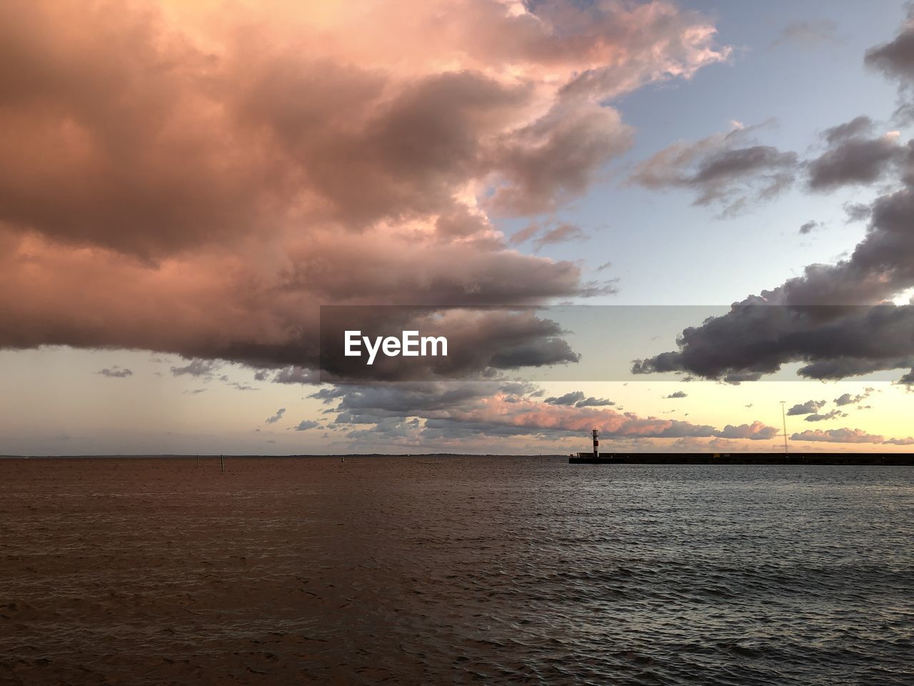 Scenic view of sea against cloudy sky during sunset