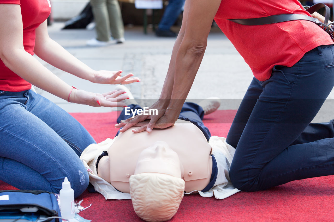 Instructor explaining rescue worker while giving cpr to mannequin