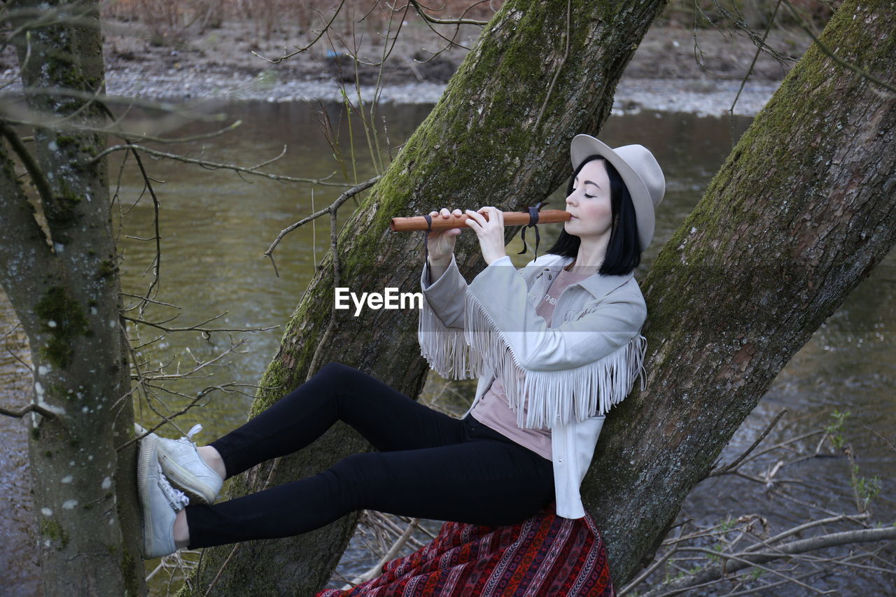 Woman playing flute on tree