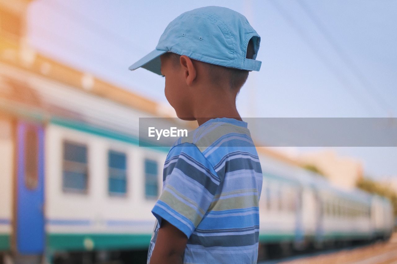 Boy looking at train against sky