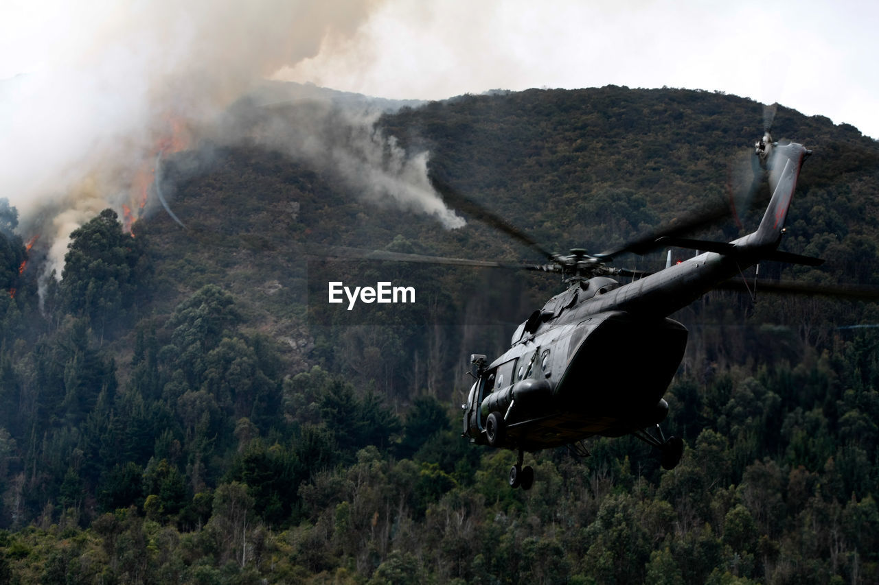 Helicopter flying against fire on mountain