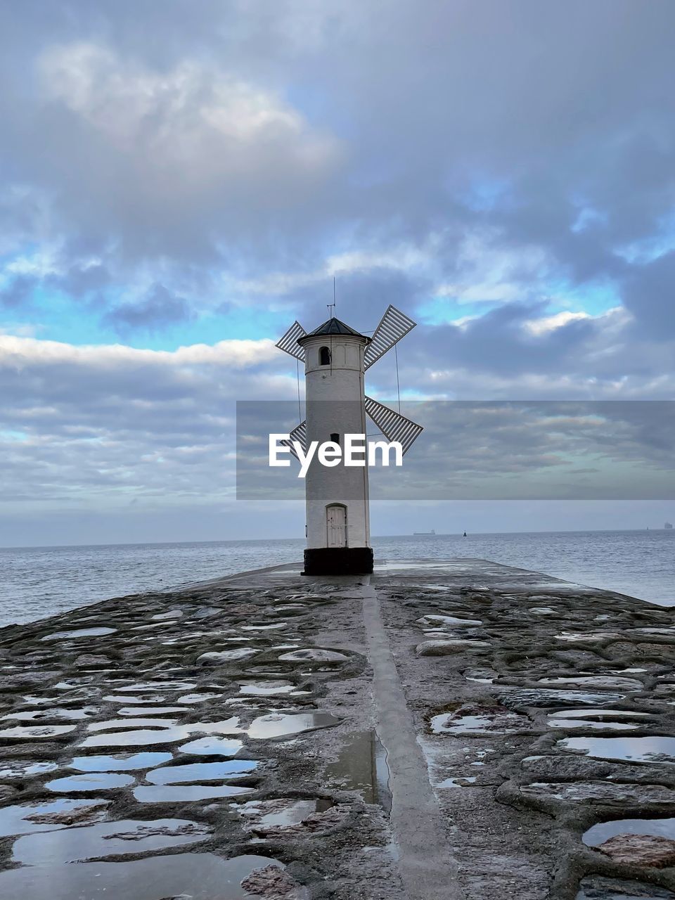 sky, sea, water, ocean, tower, coast, cloud, beach, nature, architecture, guidance, environment, land, lighthouse, shore, built structure, wind, environmental conservation, horizon over water, horizon, building, building exterior, beauty in nature, scenics - nature, wind power, no people, wind turbine, protection, security, turbine, landscape, travel, coastline, travel destinations, outdoors, renewable energy, body of water, day, tranquility, wave, windmill, blue, alternative energy