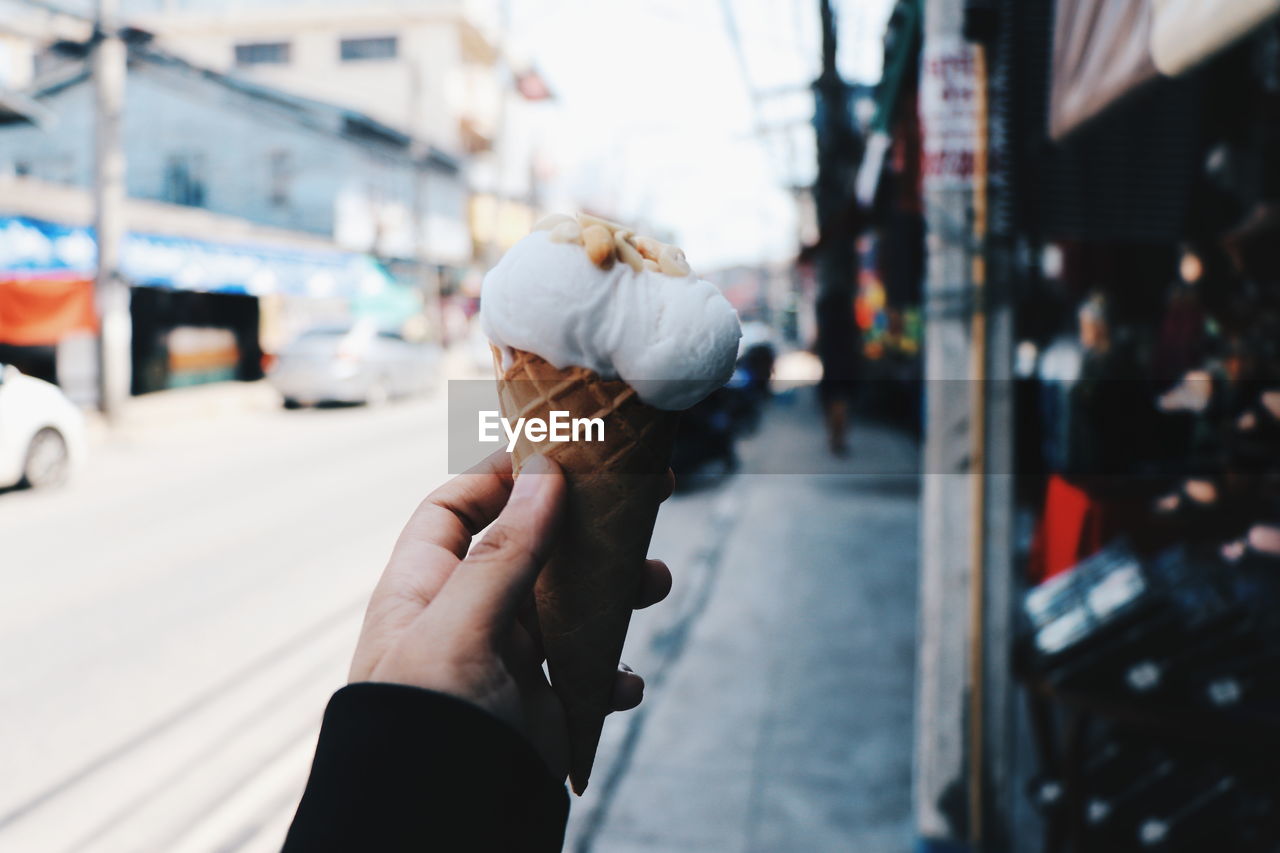 Close-up of hand holding ice cream on street