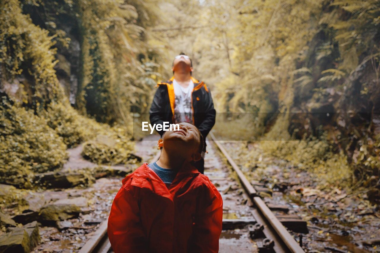 Son with father standing on railroad track in forest