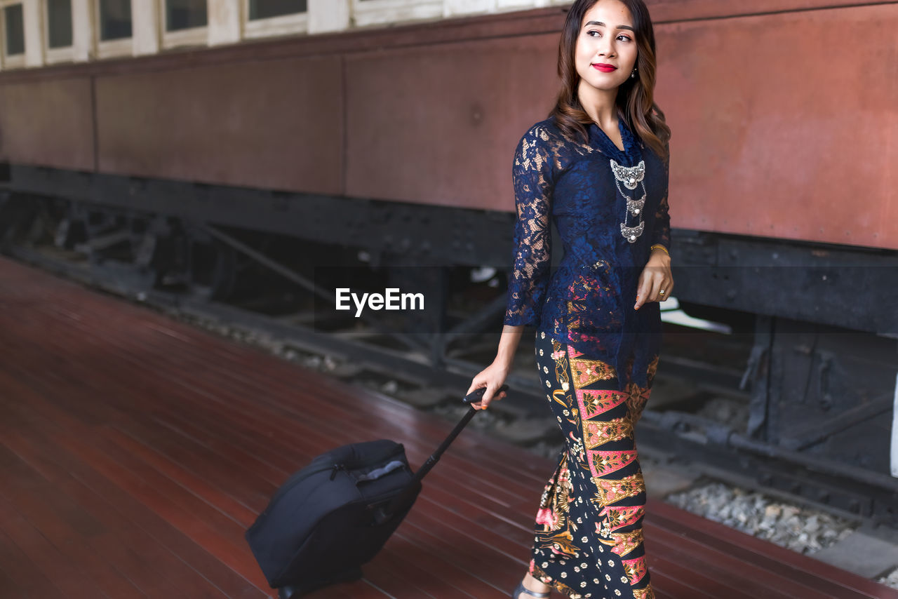 Beautiful asian malay woman travelling with carrying baggage at the train station.