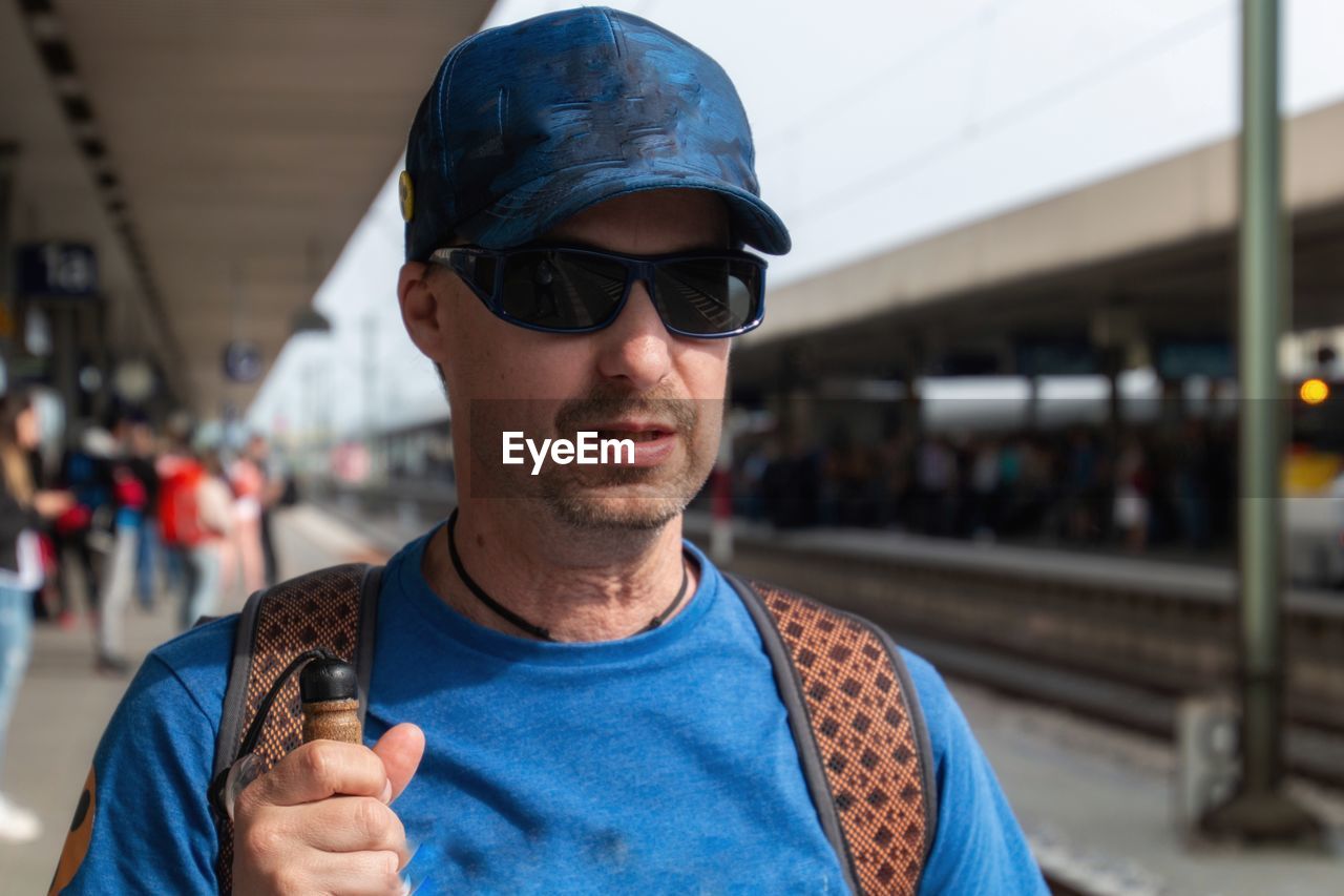 Man wearing sunglasses at railroad station platform