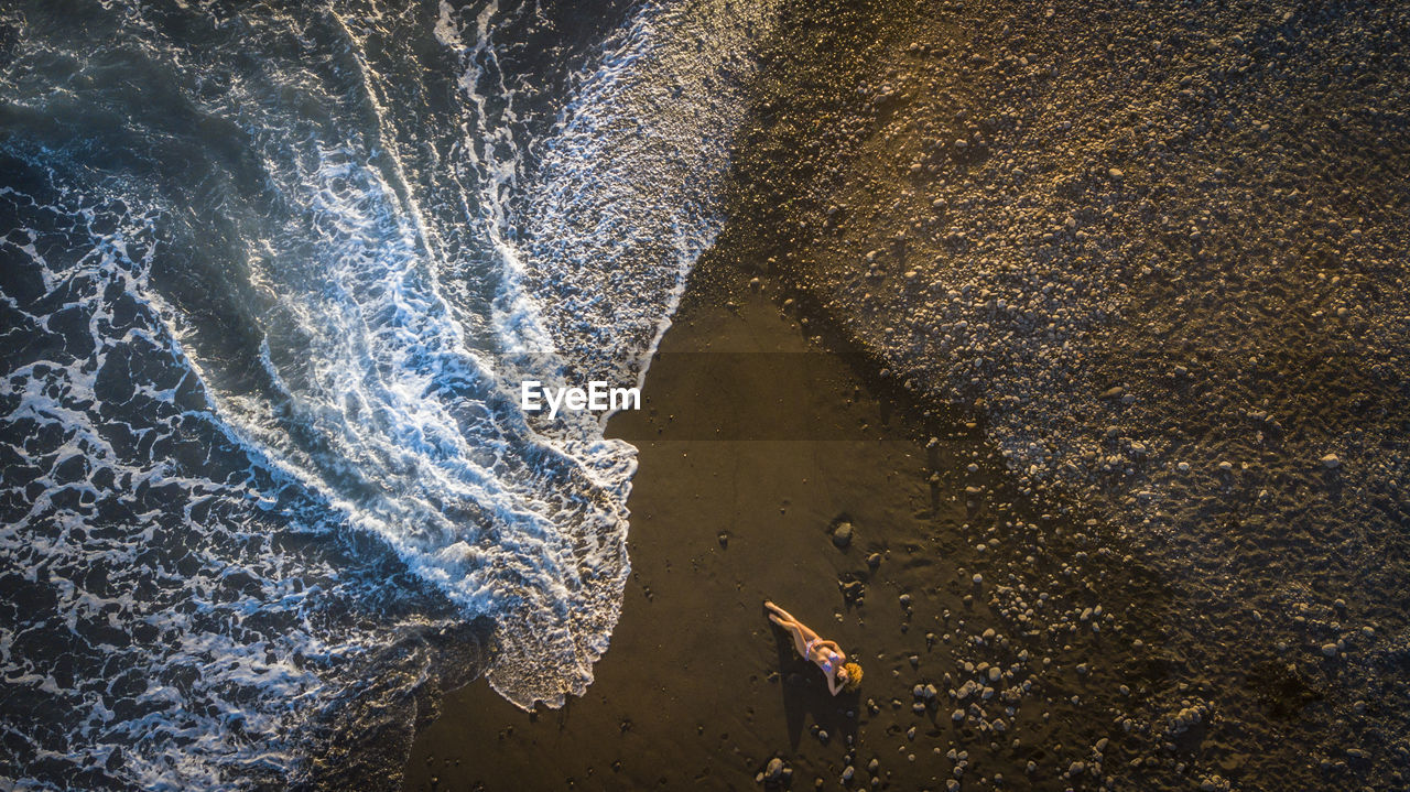 Aerial view of mature woman lying at beach