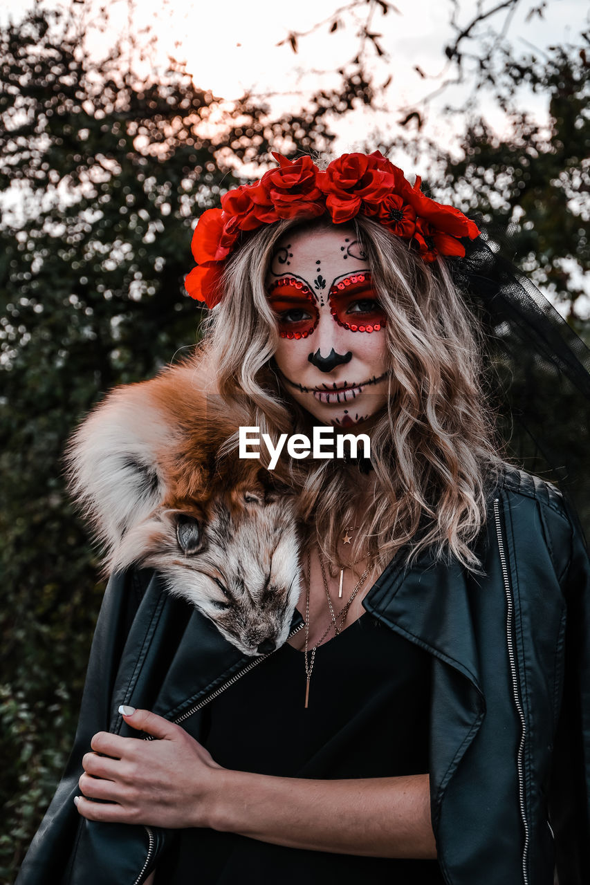 Happy halloween concept. scared horrible female sitting in special outfit, wears white clay skull