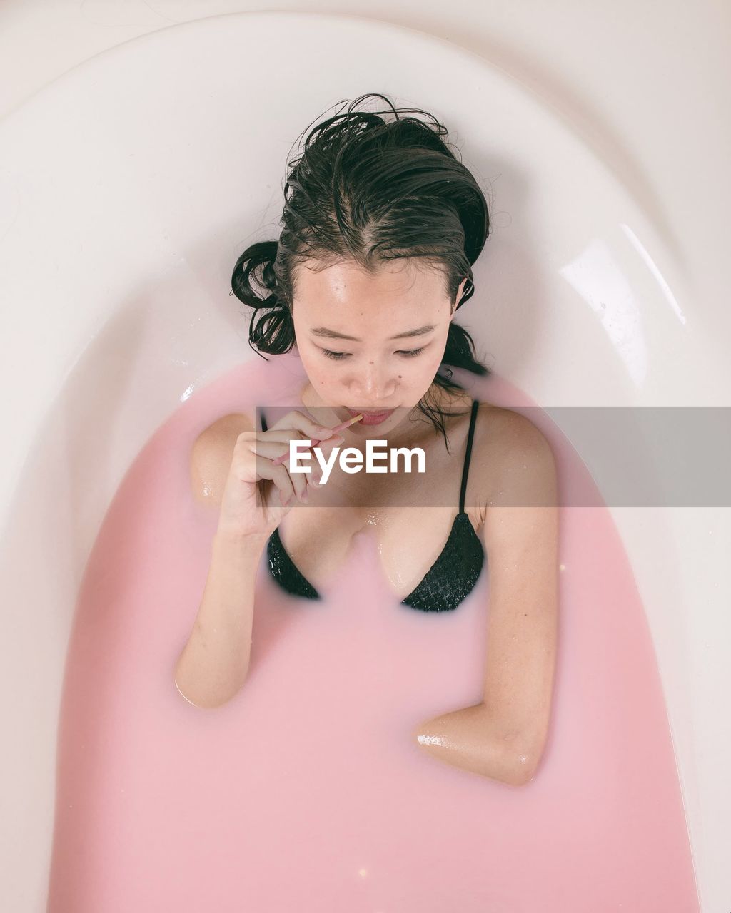 High angle view of woman having milkbath in bathtub