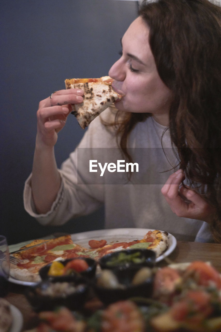 Close-up of woman eating pizza at table