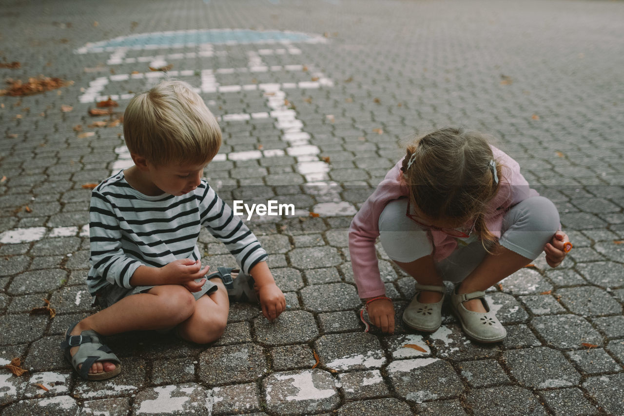 High angle view of siblings playing on cobblestone