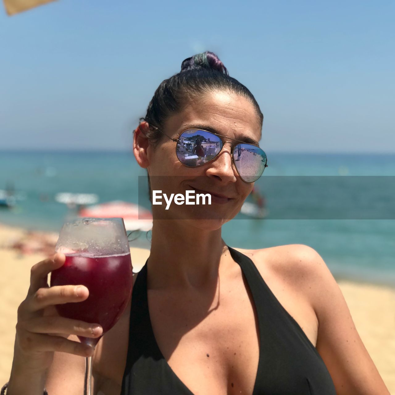 Portrait of woman holding red drink at beach