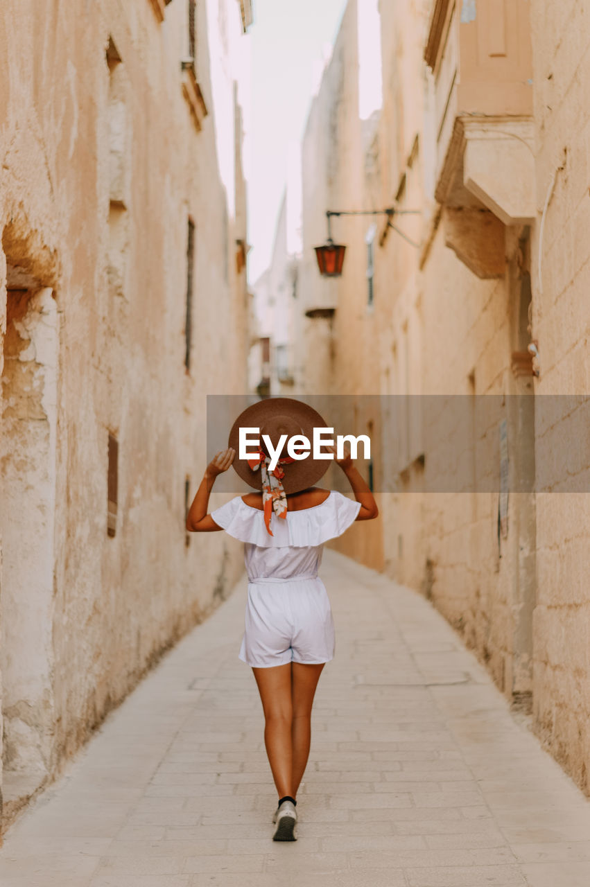 Full length of woman standing amidst buildings in silent city mdina in malta