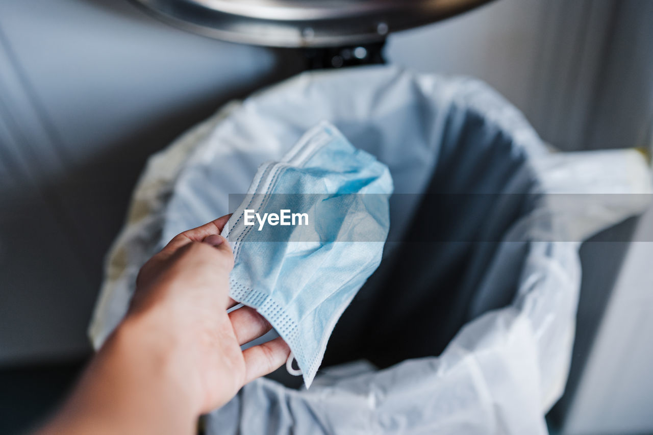Cropped hand throwing mask in dustbin