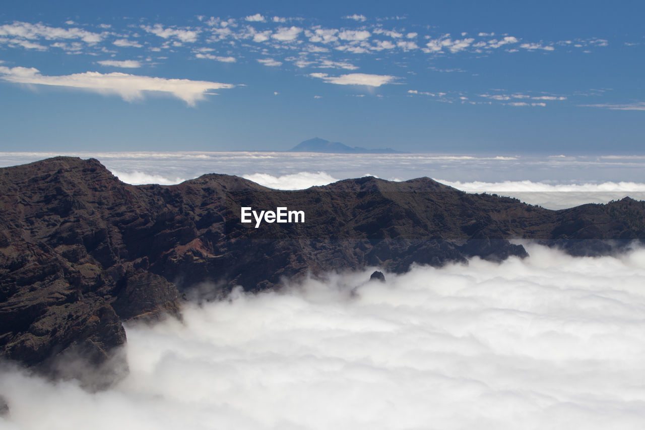 Scenic view of mountains over clouds and teide over horizon