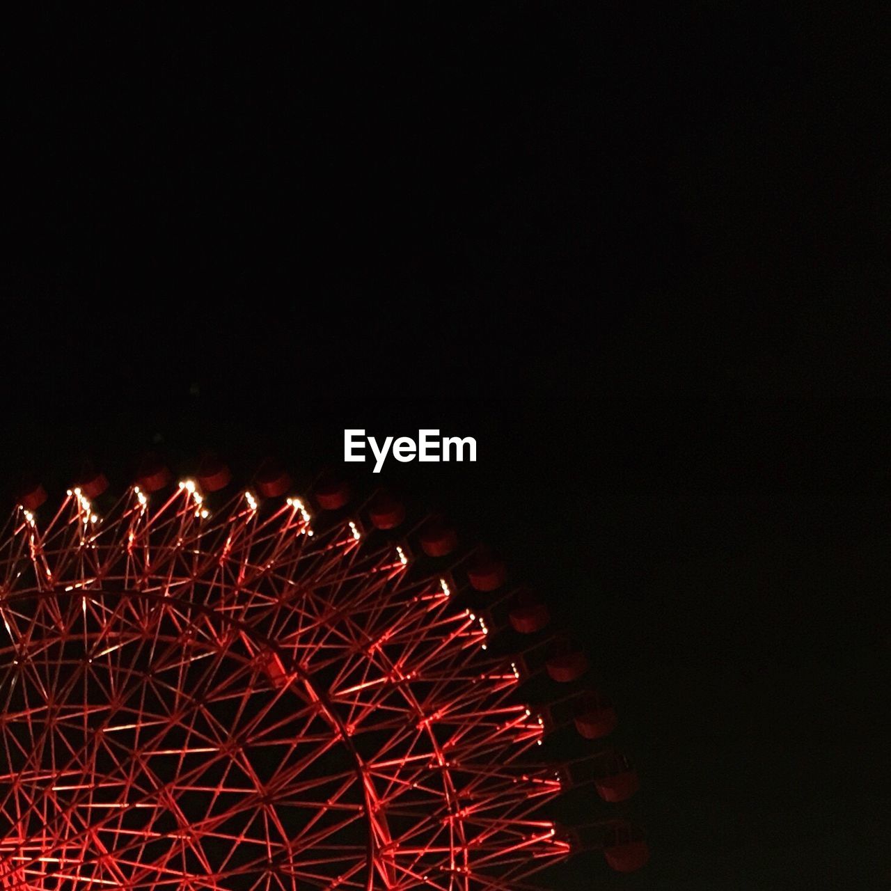 Low angle view of illuminated red ferris wheel against clear sky at night