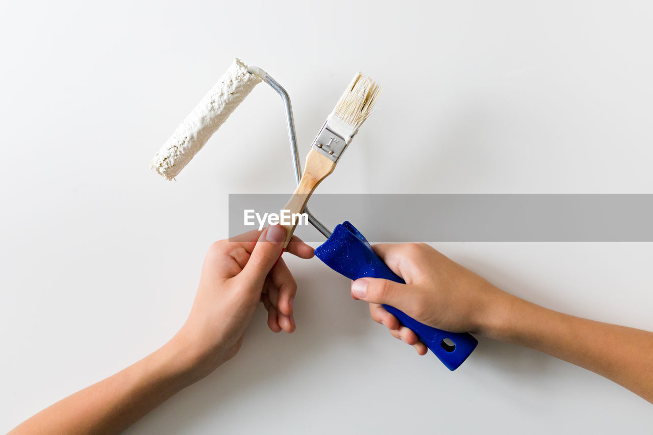 cropped hand of woman holding paintbrush over white background