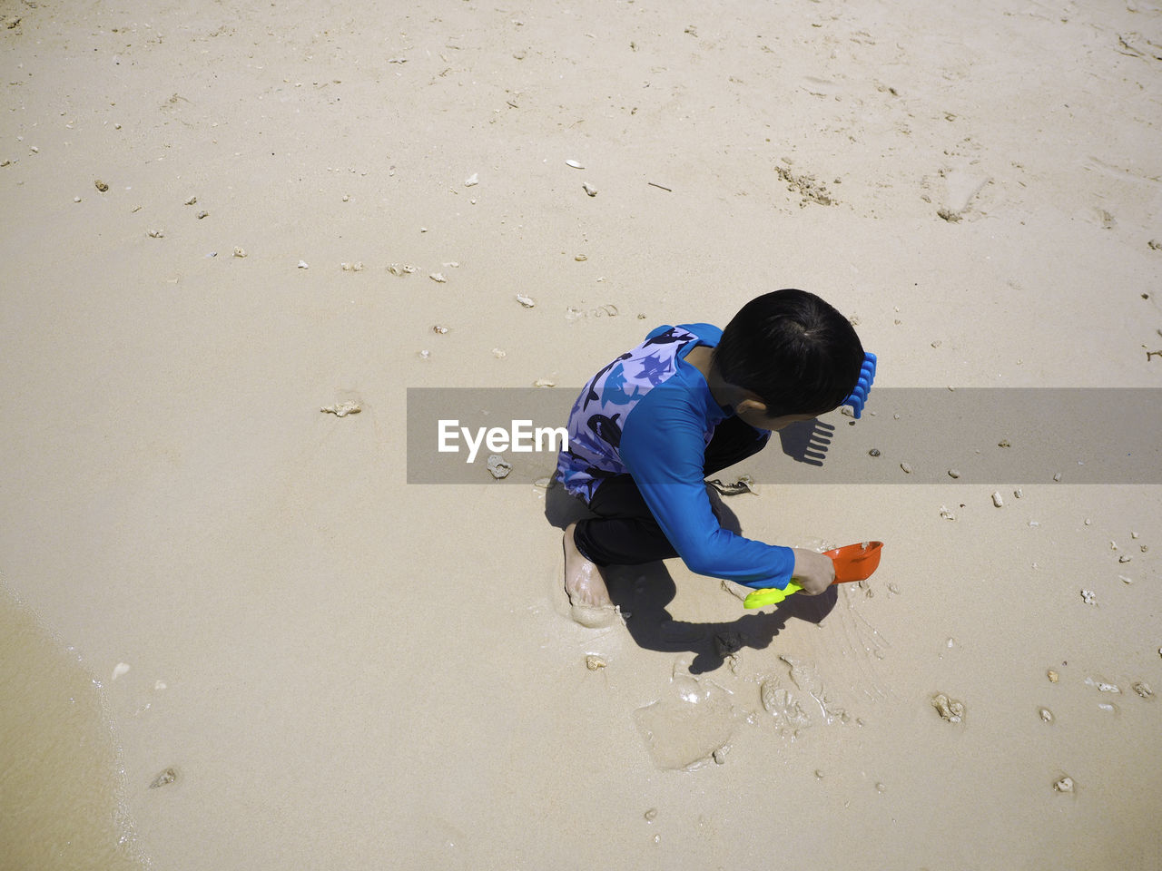 HIGH ANGLE VIEW OF BOY PLAYING WITH SAND ON BEACH