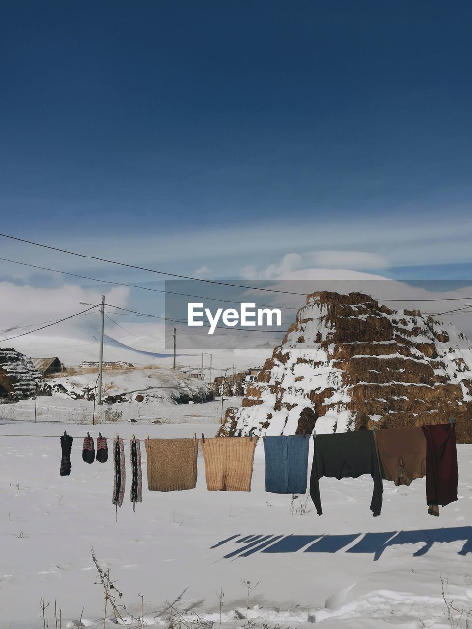 Clothes drying on snow covered field against sky
