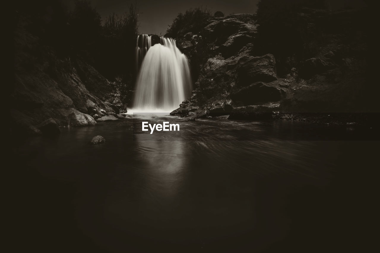 SCENIC VIEW OF WATERFALL AGAINST ROCKS