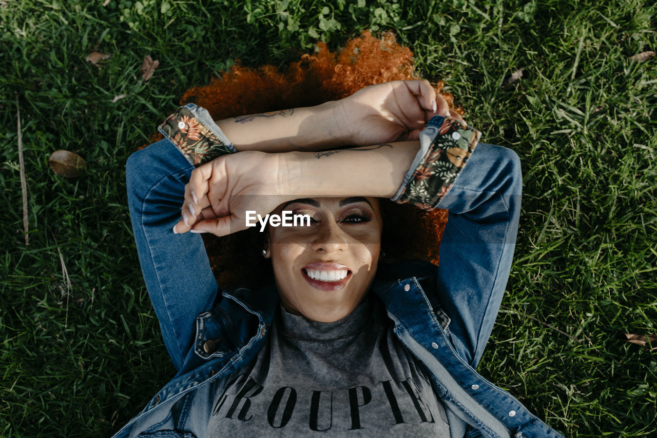 PORTRAIT OF SMILING WOMAN LYING ON GRASS