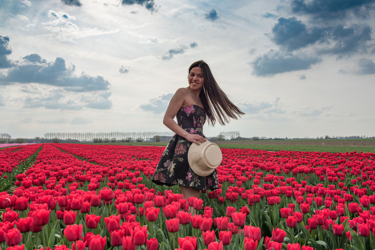 Portrait of woman standing by blooming tulips