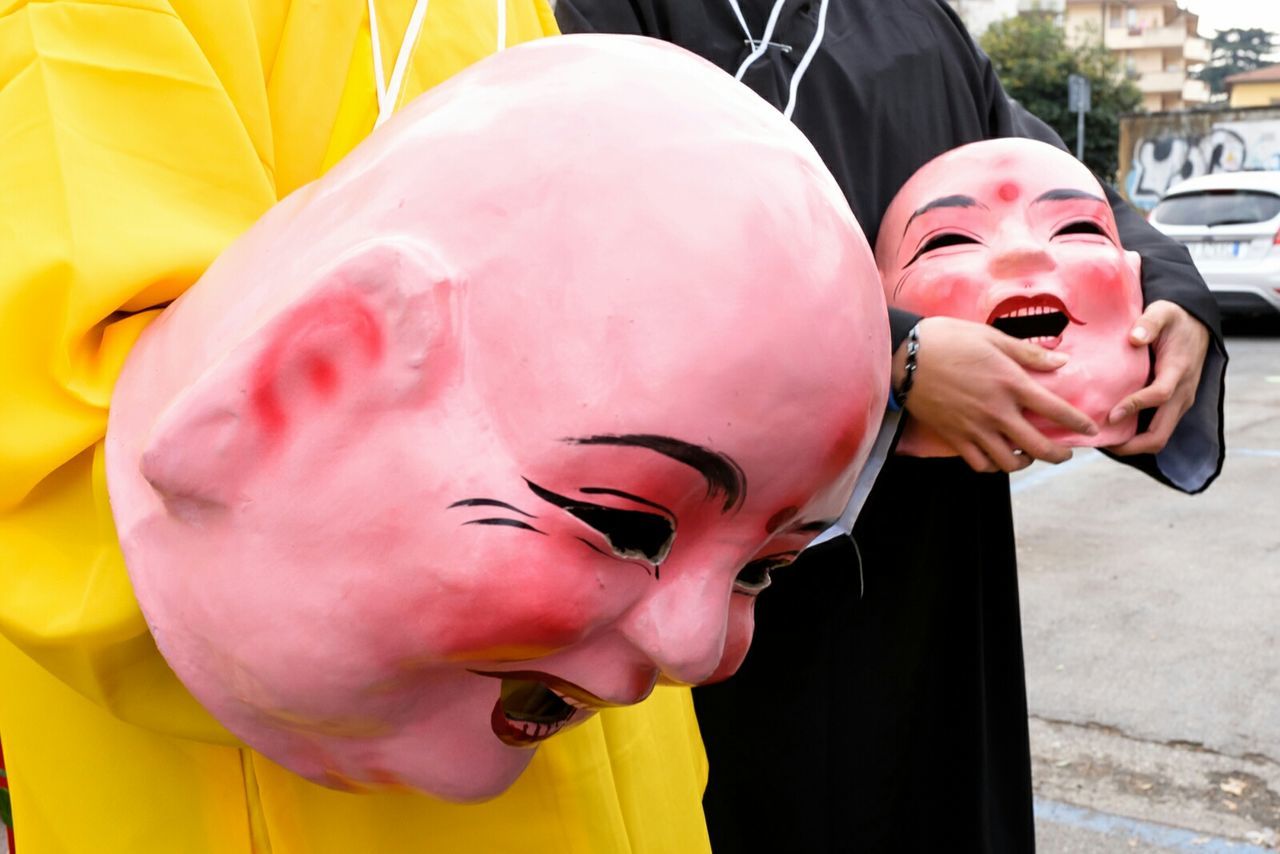 Midsection of people holding masks on street