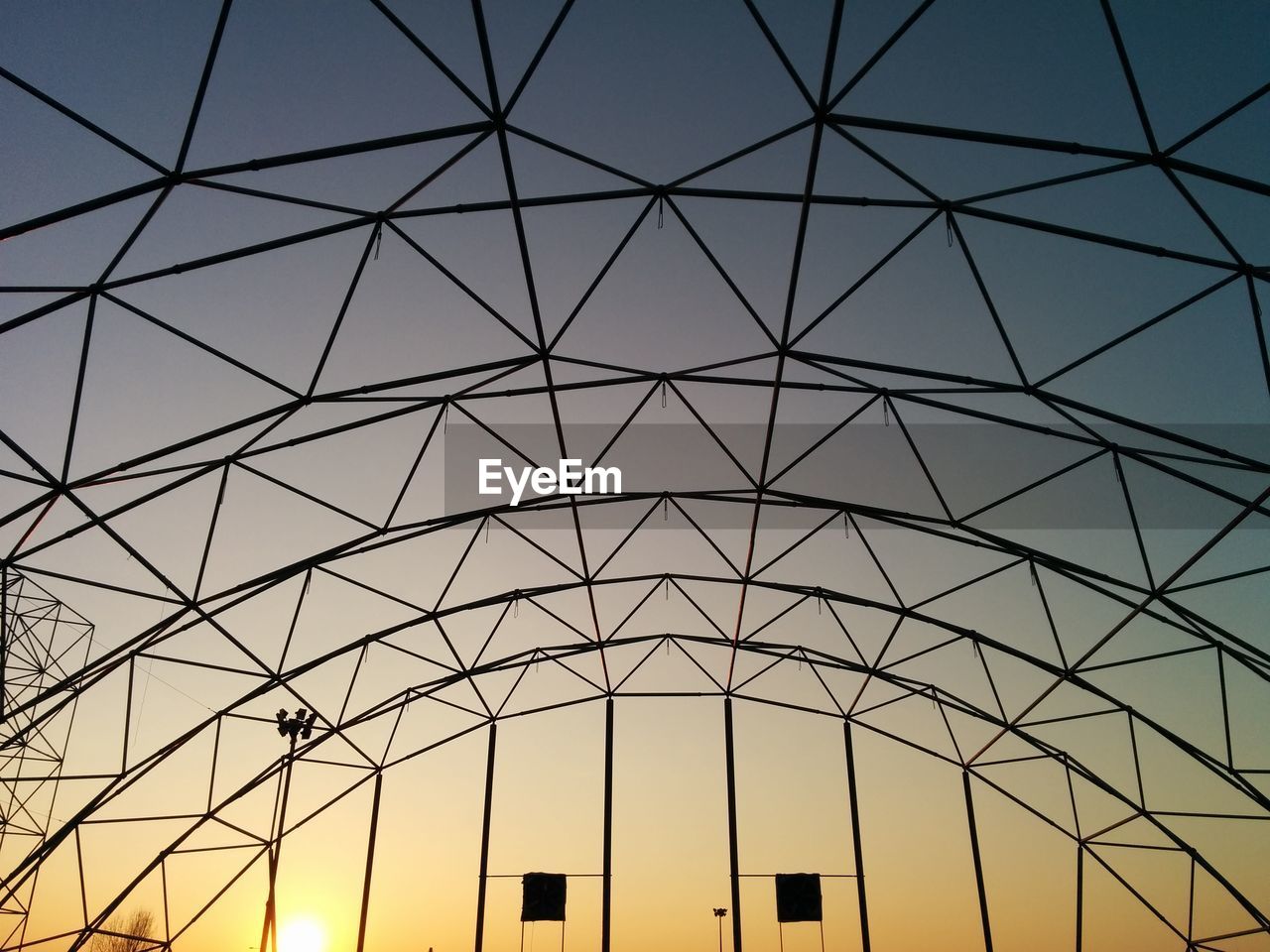 Low angle view of metallic built structure against sky during sunset