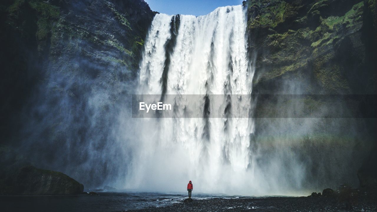 Person standing against beautiful waterfall
