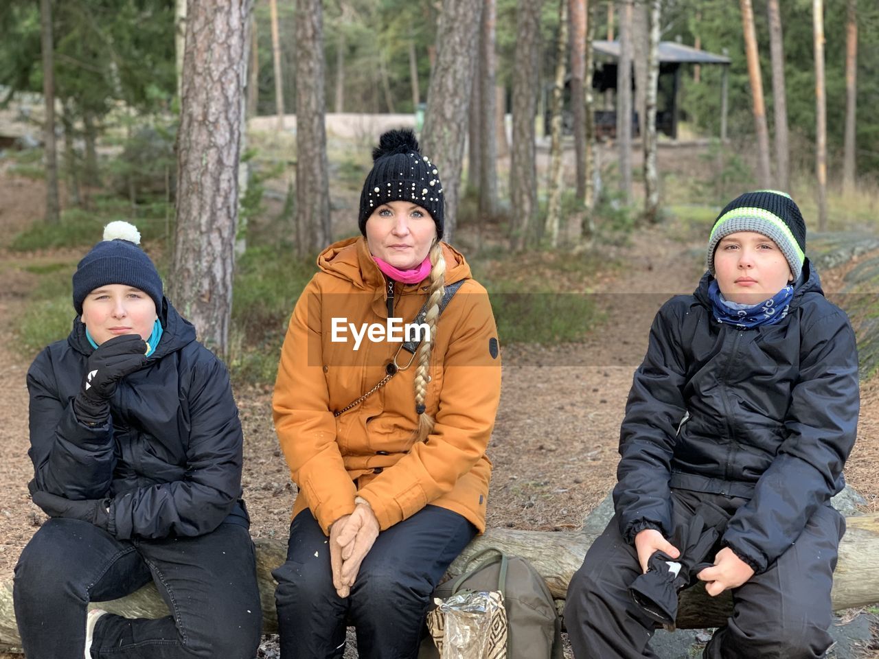 Portrait of mother and sons sitting in forest