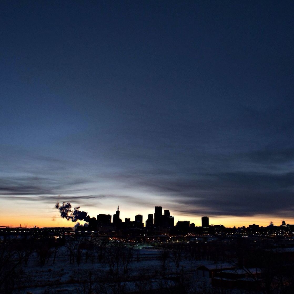 Silhouette cityscape against sky at dusk