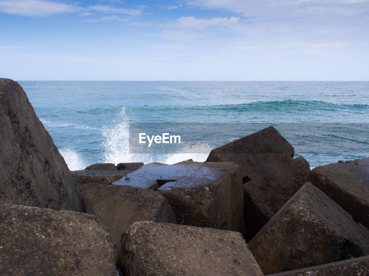 Splash of waves crashing into concrete blocks at the end of the spit