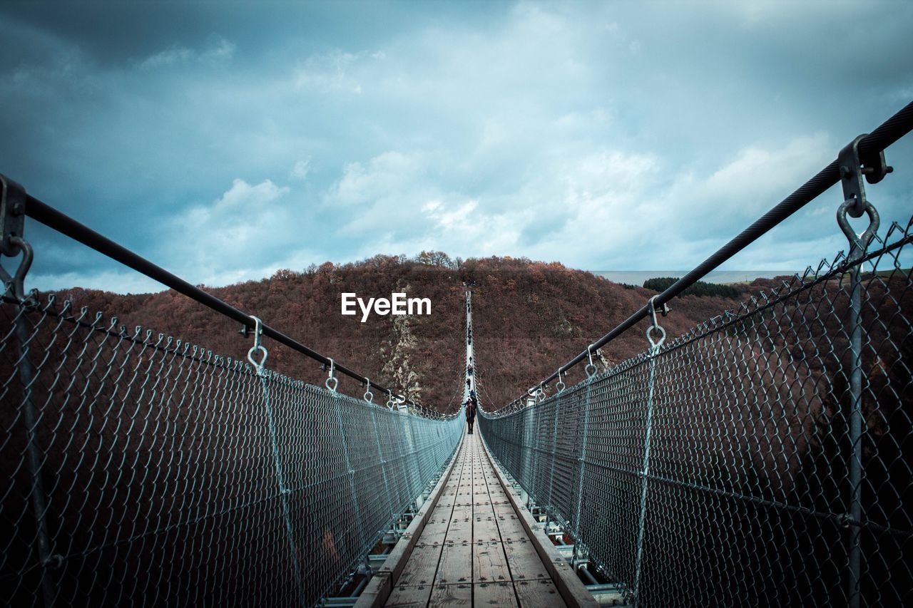Person on footbridge against mountains