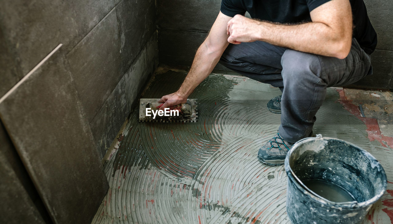 Low section of man applying cement on floor