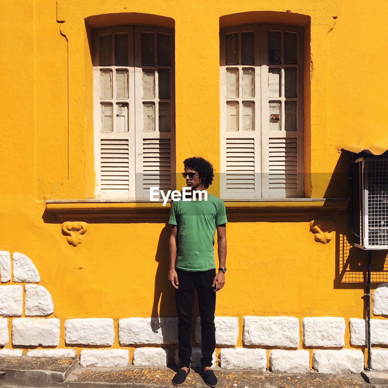 Full length of man standing against yellow building