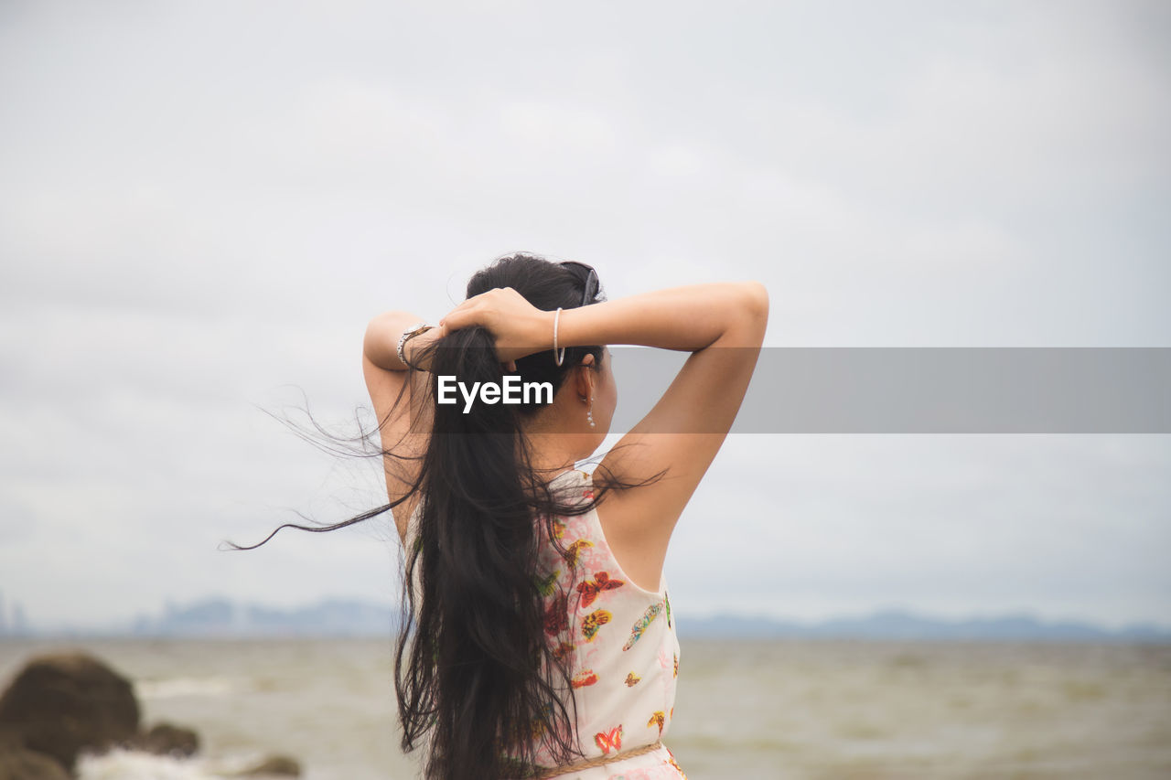 Midsection of woman standing on beach against sky