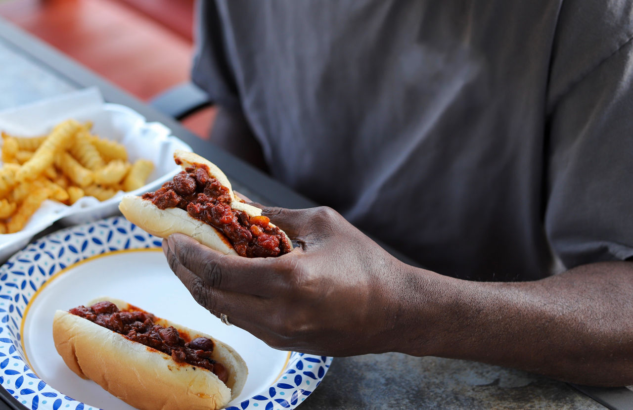 An african-american man eating a chili dog at a picnic