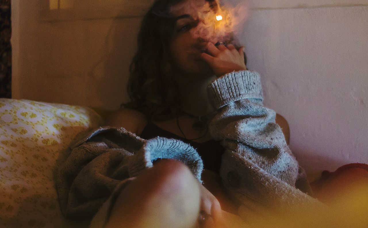 Woman smoking on bed at home