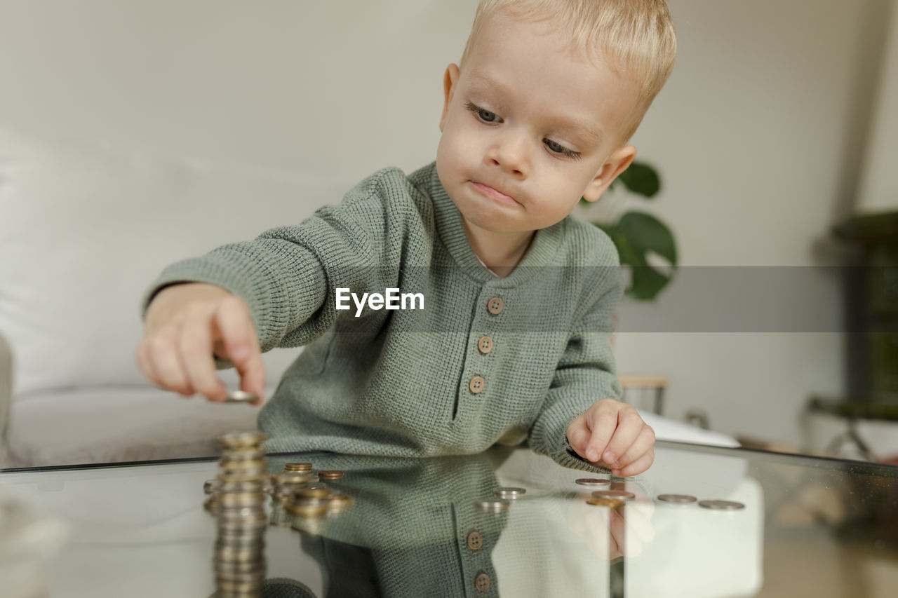 Boy counting coins on table at home